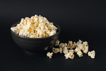 Bowl with tasty popcorn on black background