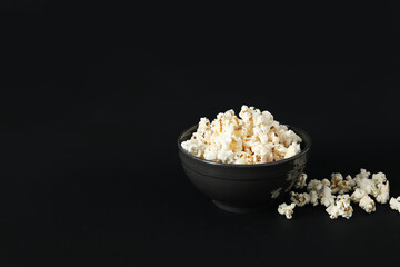 Bowl with tasty popcorn on black background