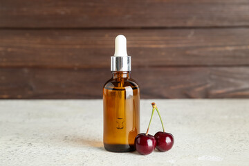 Bottle with cosmetic oil and cherries on white table