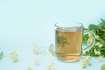 Glass cup of linden tea on blue background
