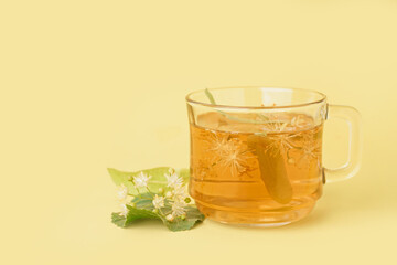 Glass cup of linden tea on yellow background