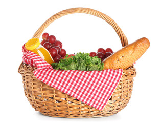 Wicker basket with tasty food for picnic and juice on white background