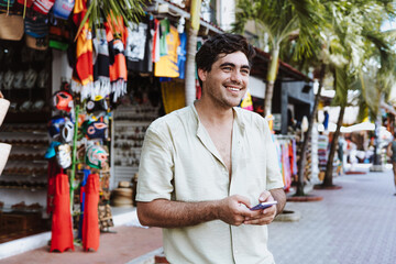 hispanic young man using mobile phone on vacations or holidays in Mexico Latin America, Caribbean and tropical destination	