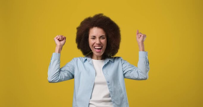 Excited happy african Winning american woman rising hands with ecstatic face expressions isolated on orange studio background
