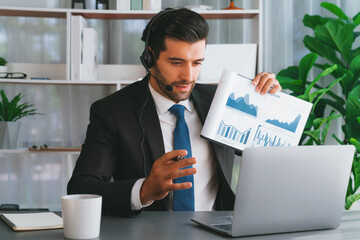 Business man wearing headphone present financial data or BI paper via laptop during online meeting....