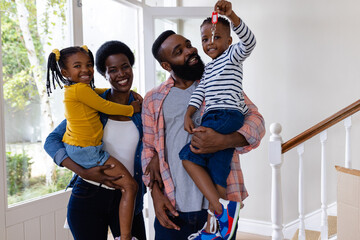 Portrait of smiling african american parents carrying children with key in new home, copy space