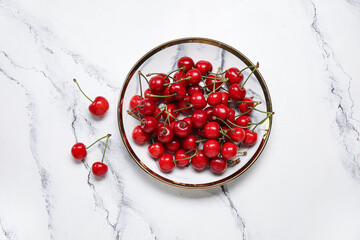 Plate with sweet cherries on white background