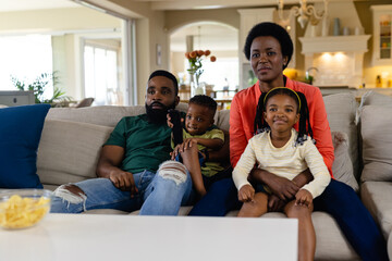 African american parents and children watching tv while sitting on sofa in living room