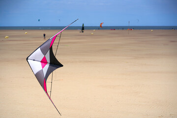 Close up of colorful stunt kite (Stabdrachen) on busy sand beach in Holland. Toy for windy days....