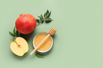 Bowl of honey, pomegranate and apple for Rosh Hashanah celebration (Jewish New Year) on green background