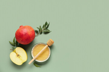 Bowl of honey, pomegranate and apple for Rosh Hashanah celebration (Jewish New Year) on green...