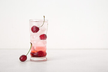 Glass of tasty cherry lemonade on white background