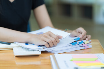 Businesswoman hands working in Stacks of paper files for searching and checking unfinished document...