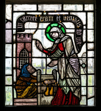 Stained glass church window with scenes of mercy and the lives of saints	