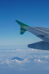 Fototapeta premium Clear blue sky with fluffy ornamental cumulus clouds, panoramic view from an airplane, wing close-up. Dreamlike cloudscape. Travel, tourism, vacations, weekend, freedom, peace, hope, heaven concepts. 