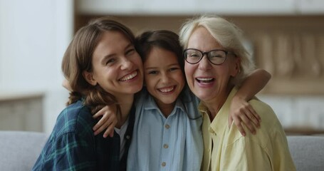 Close up portrait three loving female generations look at camera, pose for picture, enjoy leisure and priceless time together, cute girl hug mom and granny in living room shows family unity and bond - Powered by Adobe