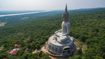 Obraz premium .aerial view Big white buddha statue on mountain for thai people travel visit and respect .praying at Wat Roi Phra Phutthabat Phu Manorom on May 15, 2017 in Mukdahan, Thailand. Kong river background..