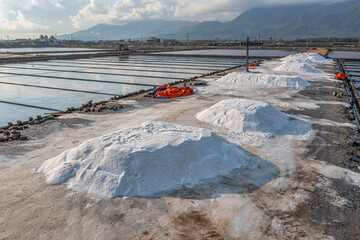 Field and Sea salt pile pyramid ready for harvest in salt farm. Sea salt is salt that is produced...