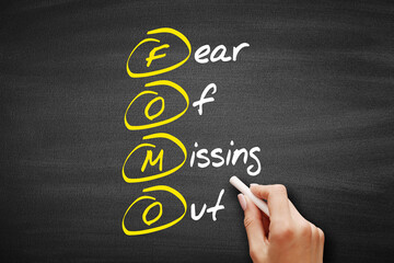 FOMO - Fear Of Missing Out, acronym concept on blackboard