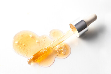 Abstract pipette dropper with orange liquid drops and smer with bubbles onwhite background. Concept...