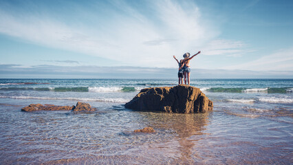Woman and son standing on rock enjoying panoramic view of atlantic ocean- travel destination,...