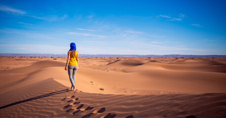 Woman tourist walking on sand dune in Sahara desert- travel destination, adventure, wanderlust...