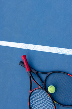 Overhead of tennis ball and tennis rackets on tennis court, copy space