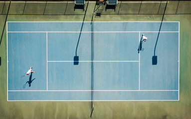 Aerial view of diverse male tennis players playing match on sunny outdoor court, copy space