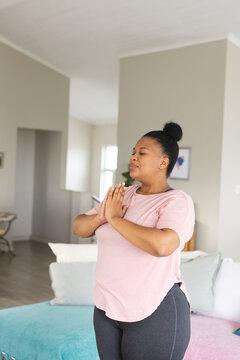 Happy african american woman doing yoga and meditating in living room