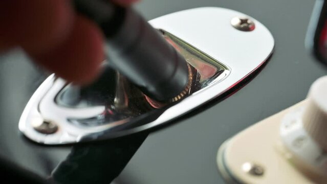 Man plugging in the guitar jack into the guitar. 4k video footage UHD 3840x2160