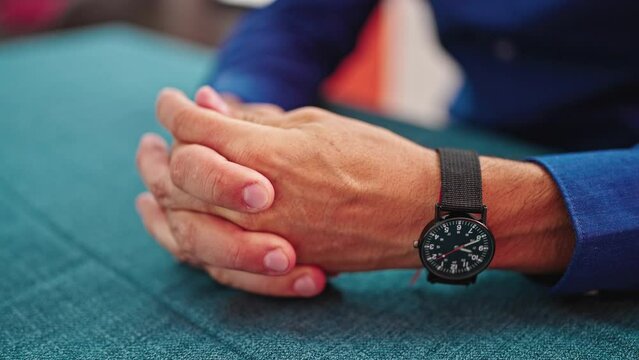 Young hispanic man moving figers with hands together at dinning room