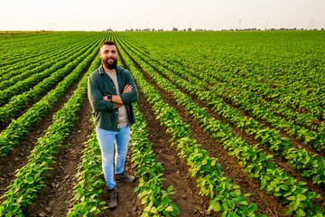Portrait of farmer who is cultivating soybean. He is satisfied with good progress of plants....