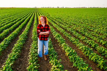 Portrait of female farmer who is cultivating soybean. She is satisfied with good progress of plants. Agricultural occupation.