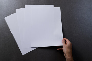 Hand of caucasian woman holding piece of paper over paper pieces with copy space on black background - Powered by Adobe