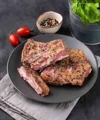 Grilled bbq lamb ribs with tomato and fresh herb on a plate on a  dark background close up. Food concept cooked in a smoker