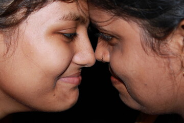 Two young beautiful Indian girl and woman on a black background.