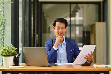 Image of confident male analyst working bookkeeping documents, checking financial data at office