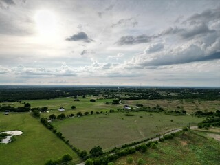 Aerial view of lush green grass fields, set against a cloudy sky