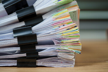 Piles of white papers Stacks of office working paper documents files with black clip on the desk in...