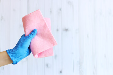 Viscose cleaning wipes. A woman's hand in a blue latex glove holds cleaning wipes. Hand with a rag for cleaning on a wooden background. The concept of professional cleaning. copy space