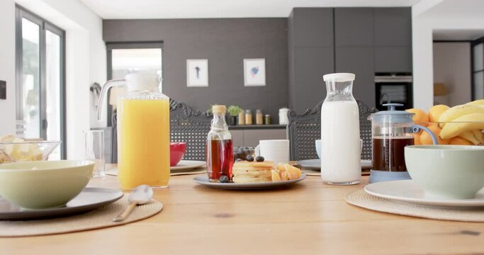 Close up of table with breakfast food and drinks in kitchen, slow motion