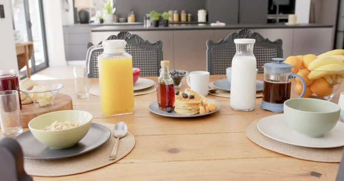 Close up of table with breakfast food and drinks in kitchen, slow motion
