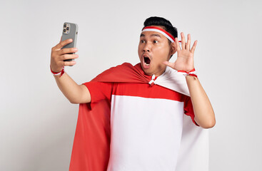 Surprised handsome young Asian man in casual white t-shirt using mobile phone and open mouth...