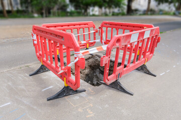 red plastic protective barriers for road works. barriers around pit on the road.