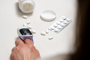 Woman using finger pulse oximeter, healthcare monitoring concept.