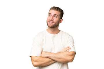Young handsome caucasian man isolated on green chroma background looking up while smiling