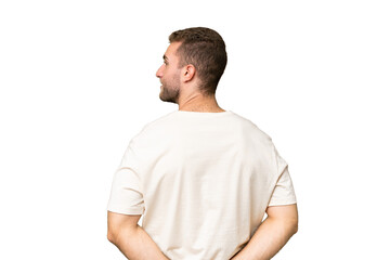 Fototapeta premium Young handsome caucasian man isolated on green chroma background in back position and looking back