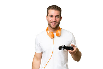 Young handsome man playing with a video game controller isolated on green chroma background smiling...