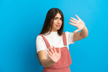 Fototapeta premium Young caucasian woman isolated on blue background nervous stretching hands to the front