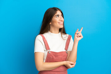 Fototapeta premium Young caucasian woman isolated on blue background pointing up a great idea